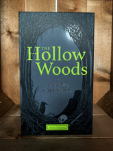 Load image into Gallery viewer, Image of the front of the box for The Hollow Woods: Storytelling Card Game. The box has a grey background, with a black illustration of an eerie forest scene arched around the sides. The title is written in vibrant green text in the center. 