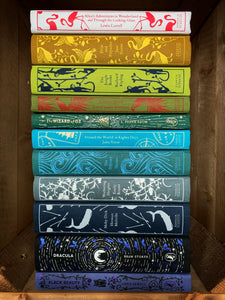 Image shows a stack of the clothbound classics with the spines facing outwards. Books from top to bottom are: Alice's Adventures in Wonderland, Pride and Prejudice, The Jungle Book, Treasure Island, The Wizard of Oz, Around the World in 80 Days, The Odyssey, Wuthering Heights, Moby Dick, Dracula, and Black Beauty.
