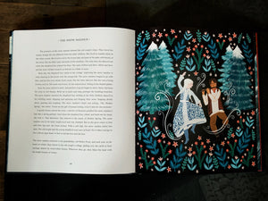 Image of a flatlay of the book Winter Tales. The book is open on pages from the story of The Snow Queen. One page is plain text, and the other is an illustration of a forest scene, with a woman dancing with a man playing a flute.
