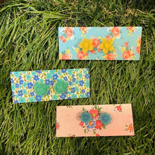 Load image into Gallery viewer, Image shows three designs of earrings yellow daffodils, aqua roses and blue daisies all made from acrylic shown displayed on fake grass.