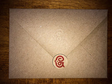 Load image into Gallery viewer, Detail of the kraft brown envelope with the embossed Grimm &amp; Co &#39;G&#39; monogram on the flap, and a sticker used as an envelope seal