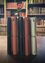 Load image into Gallery viewer, Image shows range of colours available in the vegan leather journals, choice of black, nutmeg, midnight blue, burgundy, or light blue.