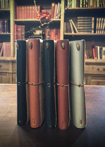 Image shows range of colours available in the vegan leather journals, choice of black, nutmeg, midnight blue, burgundy, or light blue.