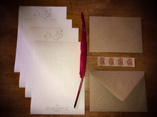 Load image into Gallery viewer, Image shows the opened Letter Writing Supplies containing 8 sheets of cream textured paper printed with a design of potion bottles and wording, a red biro quill, 4 kraft envelops embossed with the Grimm &amp; Co &#39;G&#39; monogram and set of 4 red monogram stickers