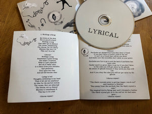 Image shows the Lyrical album CD laid out side the album cover with the lyric book open to show the first two songs and their lyrics.