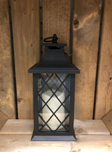 Load image into Gallery viewer, Image showing a black coloured Bright Ideas lantern with a small X lattice pattern on the windows with a battery operated candle inside and a handle on the top.