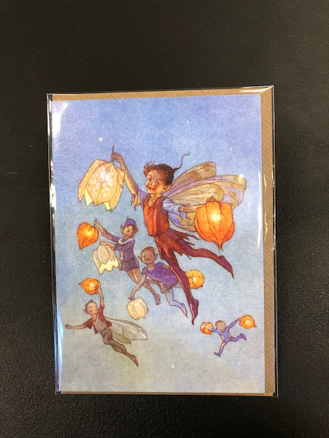 Image shows the greetings card Fairy Land with lanterns showing a full colour watercolour style illustration of fairies holding flower lanterns as they fly across an evening sky.  Card comes with a kraft envelope.