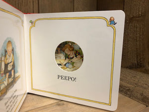 Image showing an example inside page of Peepo! with a cut out circle to peep through to the next page. Illustration through window shows the mother cooking breakfast.