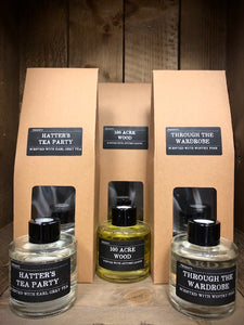 Image shows the full Scent Portal reed diffuser collection featuring Hatter's Tea Party, Hundred Acre Wood and Through the Wardrobe. Display shows the tall kraft packaging with acetate window and all 3 100ml bottles with black lids displayed in front.