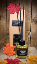 Load image into Gallery viewer, Image shows the 100 Acre Wood Scent Portal reed diffuser set with the kraft packaging and the 100ml glass bottle with black lid and reeds displayed amongst silk autumnal leaves.