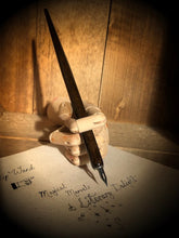 Load image into Gallery viewer, Image of a Dip Wand in a wooden mannequin hand poised above paper with cursive writing. Dip Wand is a wooden dip pen with nib for use with writing or drawing inks