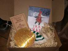 Load image into Gallery viewer, Image of the Gift Box to Mull Over containing the hardback book Letters From Father Christmas, spiced apple juice sachet, a giant chocolate coin, a knitted elf hat decoration and a jute drawstring pouch of edible elf staffs, all presented in a kraft cardboard box filled with wood wool.