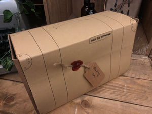 Image shows the wrapped Gift Box to Mull Over, presented as it would be delivered, ready to unwrap. Box resembles a suitcase design with a red wax seal attaching the tag.