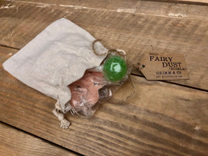 Image of a linen drawstring pouch labelled Edible Fairy Dust with a kraft paper label. Pouch is open to reveal bag inside containing coloured sherbet and a lollipop