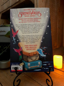 Image of the back cover of the paperback book The Strangeworlds Travel Agency, written by L.D. Lapinski. Displayed on a book stand with candles.