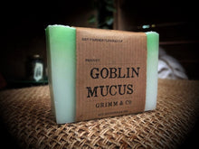 Load image into Gallery viewer, Image of Goblin Mucus bar, otherwise known as an apple and elderflower scented white and green soap slice. Soap shown with kraft paper label.