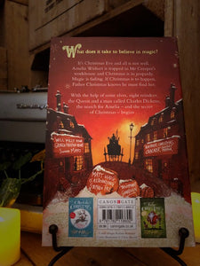 Image of the back cover of the paperback book The Girl Who Saved Christmas, written by Matt Haig and illustrated by Chris Mould. Displayed on a book stand with candles.