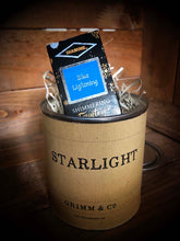 Load image into Gallery viewer, Starlight, a tin containing blue and silver shimmering ink suitable for writing and drawing. Ink box is shown poking out of tin filled with wood wool.