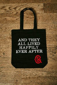 Image of black cotton tote book bag with white printed slogan on front saying 'And they all lived happily ever after' with the red Grimm & Co 'G' monogram in the bottom right corner