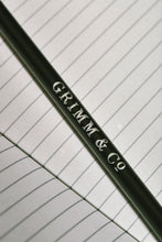 Load image into Gallery viewer, Close up details of lettering on a Word Wand, otherwise known as a black pencil with a black eraser at the top. The silver lettering in the image reads &#39;Grimm &amp; Co.&#39;