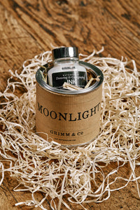 Image of a tin of Moonlight. A silver drawing or writing ink nestled in wood wool inside the tin and wrapped with a kraft paper label.