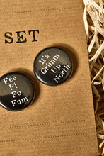 Load image into Gallery viewer, Image showing a black button badge with the slogan &#39;It&#39;s Grimm Up North&#39; printed in white text.