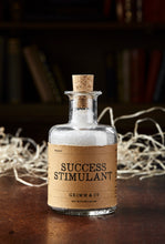 Load image into Gallery viewer, Image shows a bottle of Success Stimulant, otherwise known as white, scented bath salts in a glass bottle with cork lid and a kraft paper label