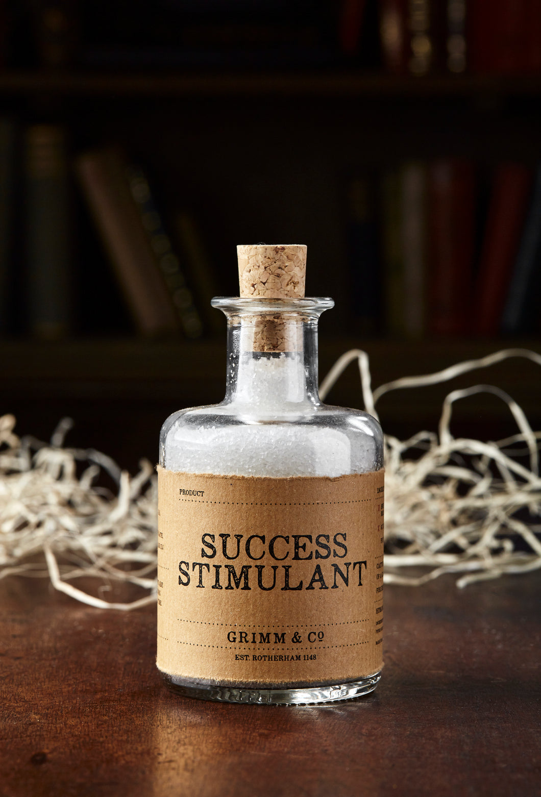 Image shows a bottle of Success Stimulant, otherwise known as white, scented bath salts in a glass bottle with cork lid and a kraft paper label