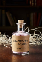 Load image into Gallery viewer, Image shows a bottle of Grandma&#39;s Scabs potion, a blass bottle with cork containing pale pink bath salts and dried rose petals. Bottle is wrapped with a kraft paper label.