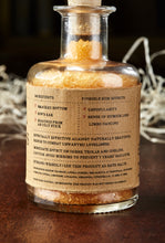 Load image into Gallery viewer, Image of the back of Eternal Ugliness, otherwise known as scented, orange bath salts in a glass bottle with cork, with label showing faux ingredients and side effects