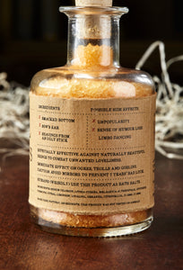 Image of the back of Eternal Ugliness, otherwise known as scented, orange bath salts in a glass bottle with cork, with label showing faux ingredients and side effects