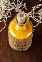 Load image into Gallery viewer, Top view image of A Pinch of Happiness otherwise known as scented yellow bath salts in a glass bottle with cork