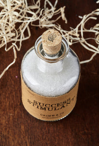 Top view of Success Stimulant potion bottle, a glass bottle and cork filled with scented white bath salts.