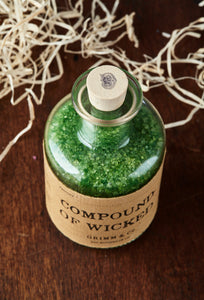 Top view image of Compound of Wicked otherwise known as scented, green bath salts in a glass bottle with cork