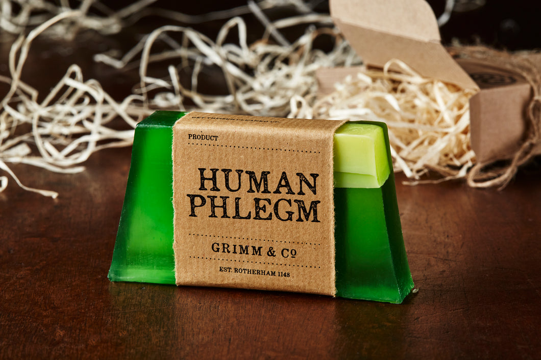 Image of Human Phlegm bar, a green and white melon scented soap slice shown with a kraft paper label. 