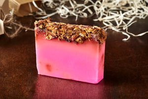 Image of Grandma's Scabs bar, otherwise known as a pink rose scented soap slice topped with dried rose petals, shown without kraft paper label