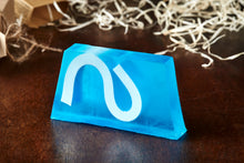 Load image into Gallery viewer, Image of Condensed Enthusiasm bar, otherwise known as an ocean scented soap slice, it is blue with a white wave shape inside the slice, shown without the kraft label
