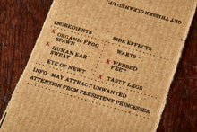 Load image into Gallery viewer, Image shows kraft paper label for Frog Spawn bar, a kiwi scented soap slice. Label lists the faux ingredients and side effects.