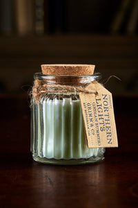 Image shows a Northern Lights Candle called Indian Summer. The candle is pale green soy wax in a small glass pot with cork lid and is cucumber scented.