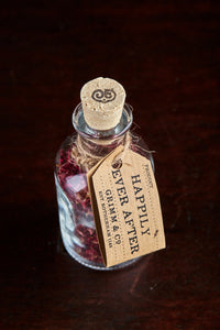 Top view image of Happily Ever After, a small decorative glass bottle with cork containing dried rose petals and tied with twine and a kraft paper label