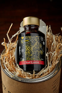 Image of Berry Sparkle, a red and gold shimmer dipping ink. Bottle of ink shown in bed of wood wool