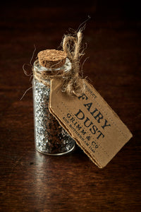 Image shows a tiny glass bottle with a cork, filled with silver glitter, and a label reading Fairy Dust.