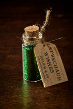 Load image into Gallery viewer, Image shows a tiny glass bottle with a cork, filled with green glitter, and a label reading Leprechaun Wishes.