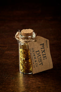 Image shows a tiny glass bottle with a cork, filled with gold glitter, and a label reading Pixie Dust.
