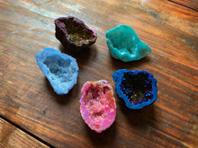 Load image into Gallery viewer, An image showing a collection of assorted colours of quartz geodes for the vacated genie geodes. These are shown inside facing up to display all the sparkling crystals inside