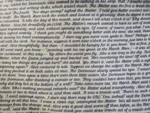 Detail of story excerpt scarf featuring text from Alice's Adventures in Wonderland in lilac cursive font on white background.