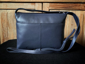 Image showing the back of the navy blue Yoshi leather cross-body handbag with back slip pocket and extendable strap shown. Design is plain navy blue on the back.