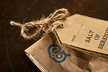 Load image into Gallery viewer, Closeup image of the Salt of Serenity label tied to the top of the brown paper tealight bag.