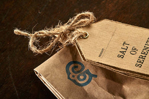 Closeup image of the Salt of Serenity label tied to the top of the brown paper tealight bag.