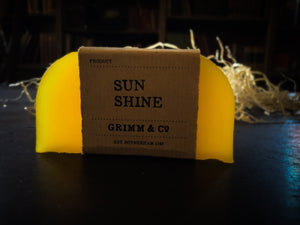 Image of a Sun Shine bar, a bright yellow solid shampoo slice with a kraft paper label